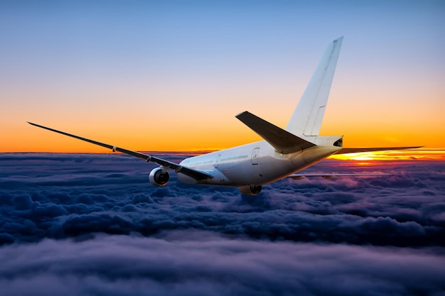 Weißes Großraum-Passagierflugzeug fliegt in den Sonnenuntergangshimmel