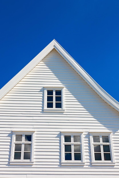 Weißes Holzhaus mit Giebel vor blauem Himmel