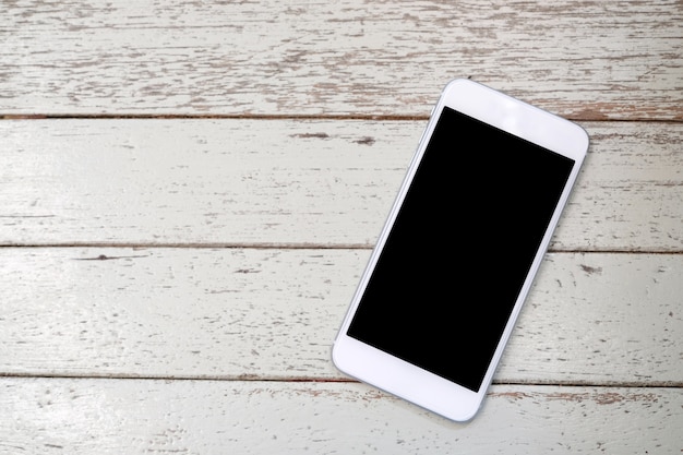 Weißes intelligentes Telefon mit leerem Bildschirm auf weißem hölzernem Hintergrund für Spott oben, mit Kopienraum