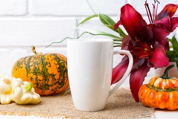 Foto weißes kaffee-cappuccino-becher-modell mit kürbis und roter lilie