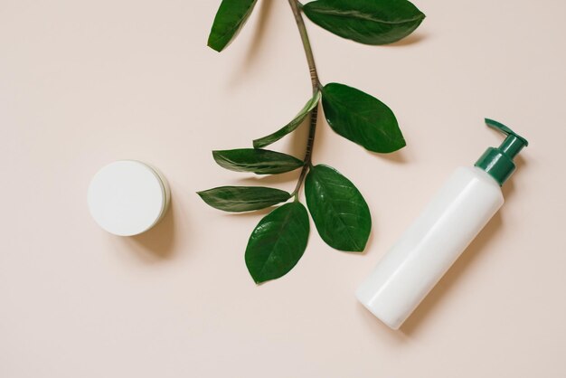 Weißes Kosmetikglas und eine Flasche Creme mit Draufsicht auf die Blätter der Pflanzen ein Mockup des Produktdesigns Natürliche Bio-Kosmetik