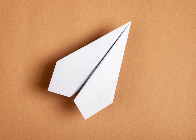 Weißes Origami-Flugzeug auf braunem Hintergrund Papierfaltkunst Architekturmodell