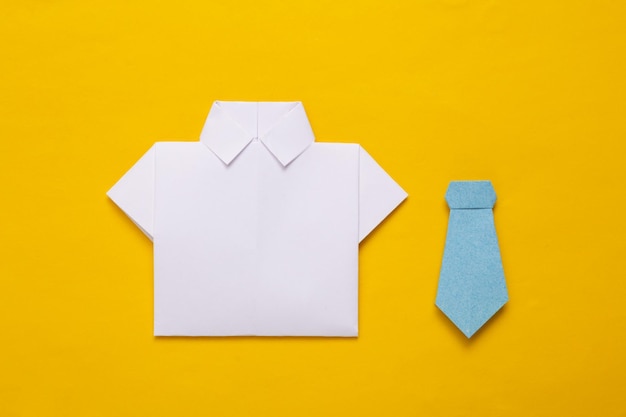 Weißes Origami-Papierhemd und Fliege auf gelbem Hintergrund
