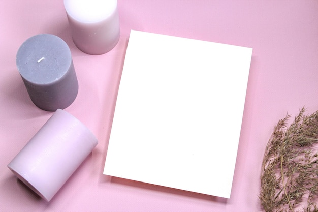 Weißes Papier leere leere aromatische Kerzen auf rosa Hintergrund Einladungskarte auf einem rosa Tisch