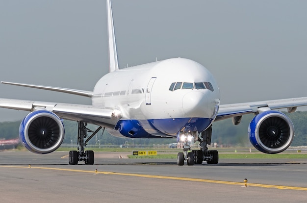 Weißes Passagierflugzeug fährt den Rollweg am Flughafen.