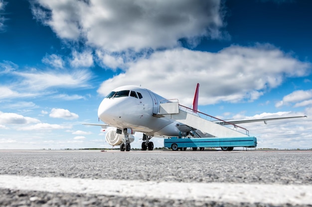 Weißes Passagierflugzeug mit Treppenwagen am Flughafenvorfeld