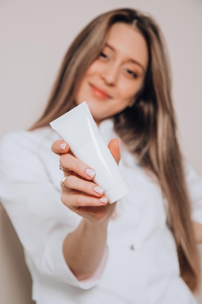 Weißes Plastikröhrchen für Creme in der Hand eines schönen Mädchens