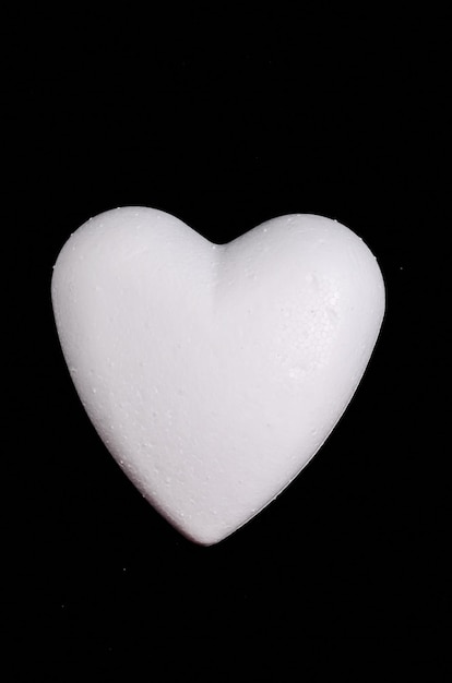 Weißes Polystyrol-Herz auf schwarzem Hintergrund