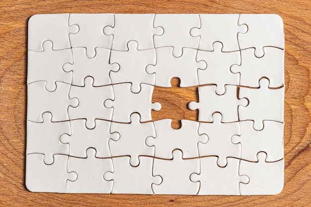 Weißes Puzzle mit fehlendem Stück auf hölzernem Hintergrund