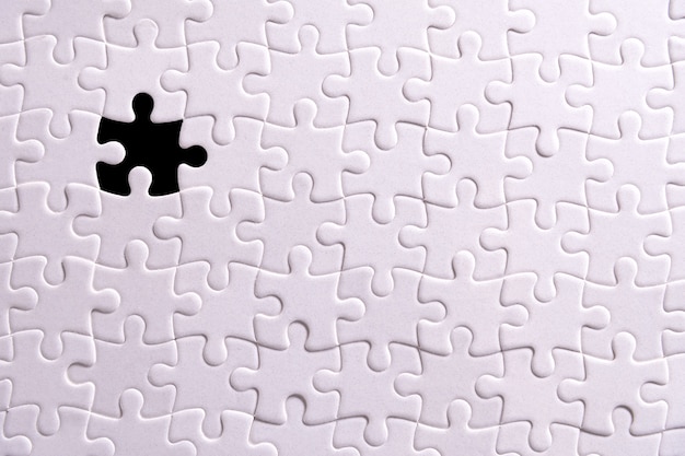 Weißes Puzzle und ein fehlendes Puzzleteil.