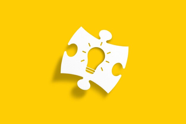 Weißes Puzzlestück mit Glühbirnenform auf gelbem Hintergrund