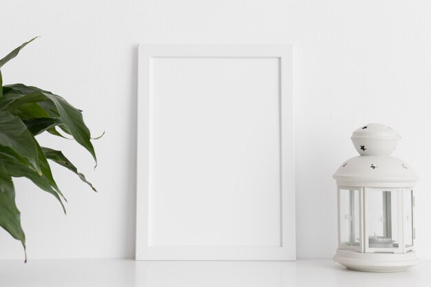 Weißes Rahmenmodell mit Spathiphyllum und Kerzenhalter auf einem weißen Tisch Hochformat