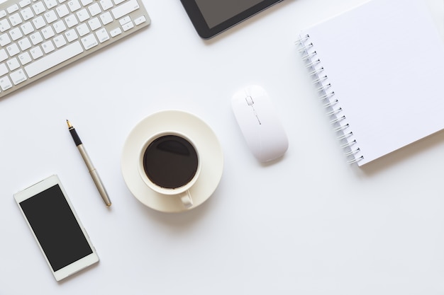 Weißes Schreibtischbüro mit Laptop, Smartphone und anderen Versorgungen mit Tasse Kaffee.