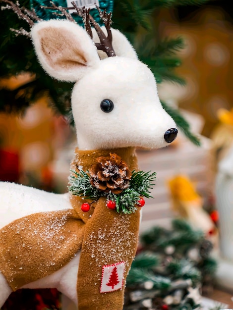 Weißes Spielzeughirsch des neuen Jahres unter einem künstlichen Weihnachtsbaum