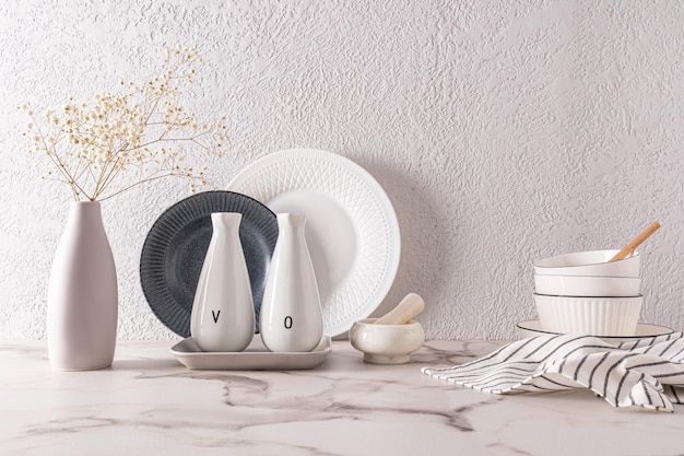 Weißes stilvolles Geschirr vor dem Hintergrund einer grau strukturierten Wand steht auf einer Marmorarbeitsplatte das Konzept eines modernen Küchenraums