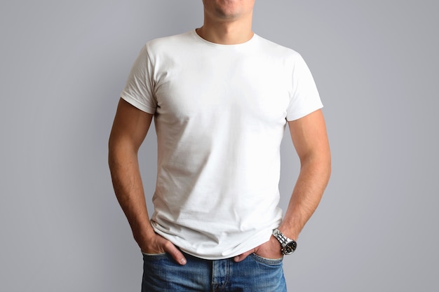 Weißes T-Shirt auf einem jungen Schimmel in Blue Jeans. isoliert auf einer grauen Wand.