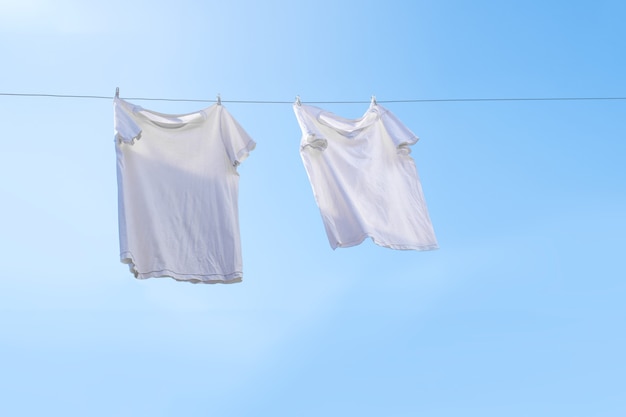 Weißes T-Shirt auf Wäscheleine vor blauem Himmel