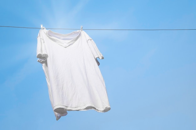 Weißes T-Shirt auf Wäscheleine vor blauem Himmel