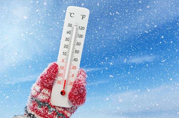Weißes Thermometer mit Celsius- und Fahrenheit-Skala in der Hand. Umgebungstemperatur minus 23 Grad Celsius