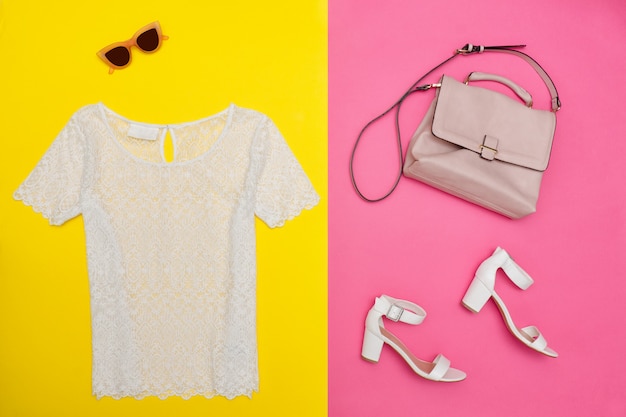 Weißes Top, Handtasche, weiße Schuhe und rosarote Brille. Helles Rosa-Gelb, Hintergrund, Nahaufnahme