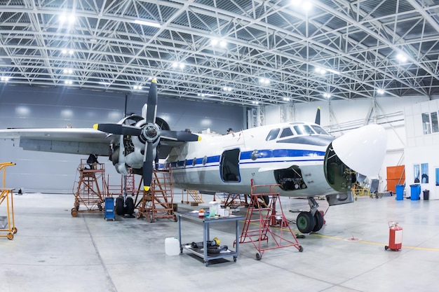 Weißes Transport-Turboprop-Flugzeug im Hangar Überprüfung mechanischer Systeme für den Flugbetrieb