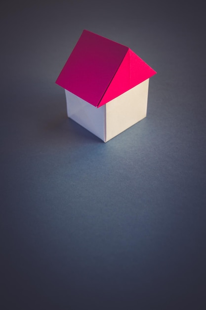 Weißes und rotes Papierhaus Origami isoliert auf grauem Hintergrund