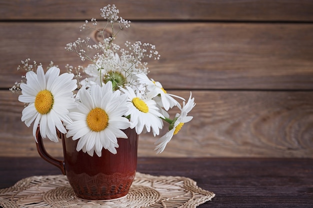 Weißes wildes Gänseblümchen blüht in einer Vase auf dem alten Tisch