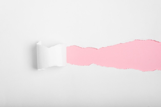 Weißes zerrissenes Papier mit rosa Hintergrund unterhalb, Platz für Text