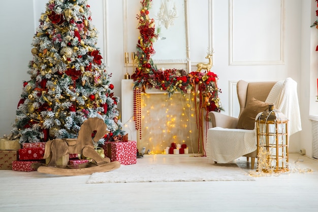 Weißes Zimmer Interieur in Rottönen mit Neujahrsbaum dekoriert, Geschenkboxen und künstlichem Kamin