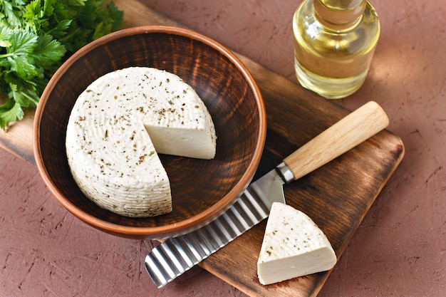 Weißkäse auf einem hölzernen Brett mit Olivenöl auf einem braunen Hintergrund