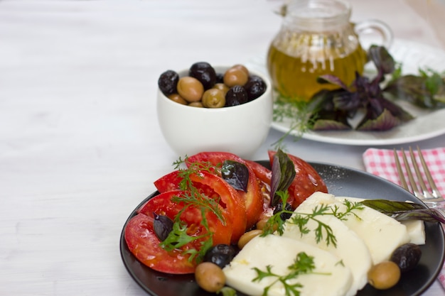 Weißkäse mit tomaten, grünen und schwarzen oliven, basilikum, koriander und olivenöl