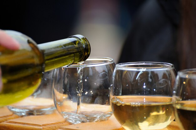 Weißwein aus einer Flasche in ein Glas gegossen