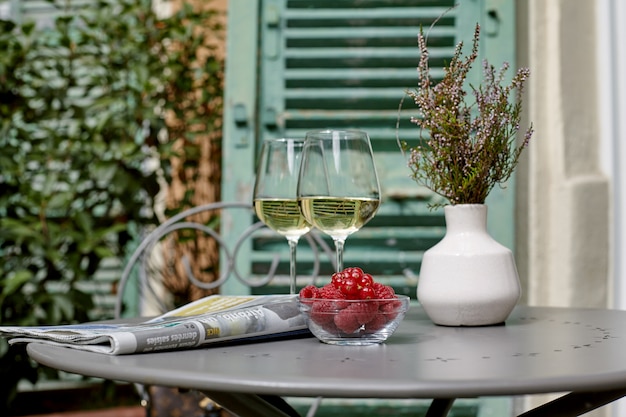 Weißwein, frische Himbeeren und rote Johannisbeeren stehen neben der Zeitung und einem Haufen Lavendel auf dem Tisch