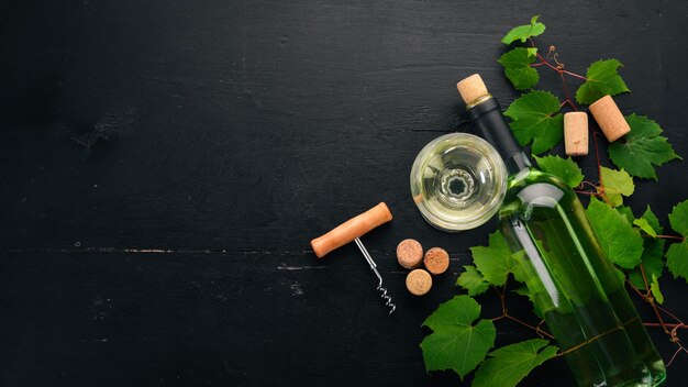 Weißwein in einer Flasche mit Glas und Trauben auf schwarzem Holzhintergrund Freier Platz für Text Ansicht von oben