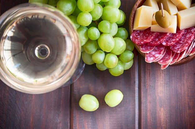 Weißwein, Trauben, Oliven und Käse auf Wolltisch