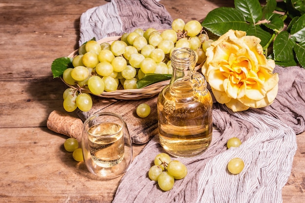 Weißwein und Traube in einem Weidenkorb. Frisches Obst, Glas und Flasche. Modernes hartes Licht, dunkler Schatten. Alte Holzbretter Hintergrund, Kopienraum