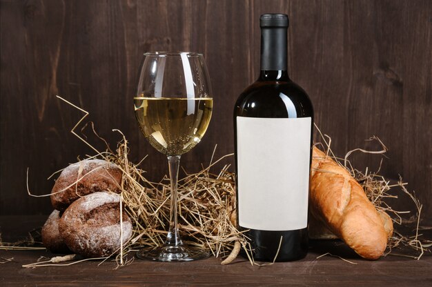 Weißweinzusammensetzung mit Brotflasche und Weinglas auf Holztisch