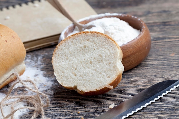 Weizenbaguette auf dem Tisch mit Mehl und verschiedenen Pflanzenkörnern