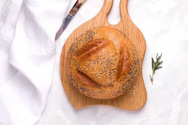 Weizenbrot mit Sesam und Mohn Nahaufnahme auf einem Holzbrett auf einem weißen Raum.