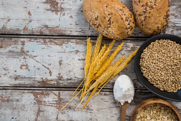 Weizenkörner mit Brötchen, Hafer und Löffel voller Mehl