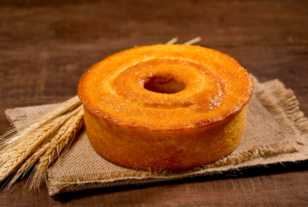 Weizenmehlkuchen auf Holz mit anderen Kuchenaromen im Hintergrund mit Weizenzweig daneben.