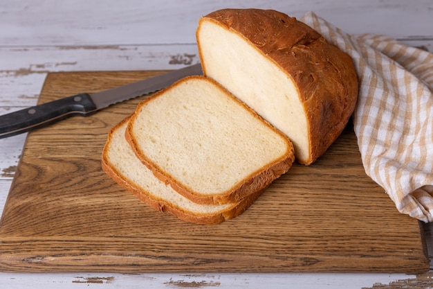 Weizenweißbrot mit knuspriger Kruste auf einem in Scheiben geschnittenen Holzbrett, hausgemacht im rustikalen Stil, selektiver Fokus-Näheaufführung