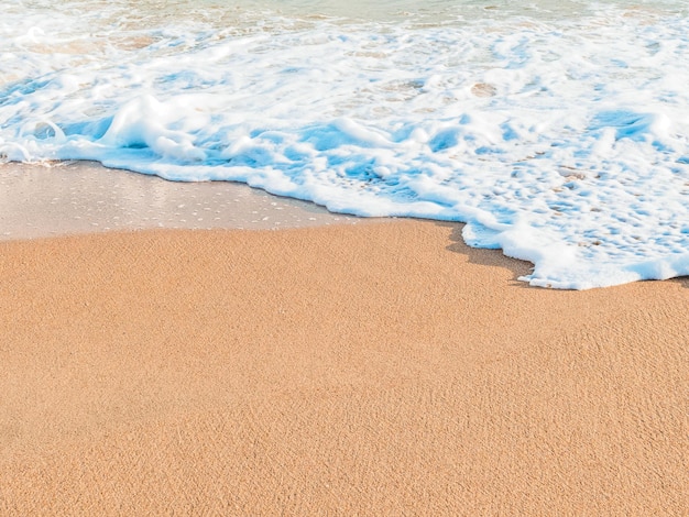 Welle an einem Sandstrand an einem sonnigen Tag kopieren