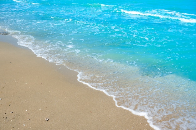 Welle des blauen Wassers auf Strandsand