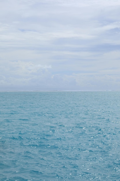 Wellen auf türkisfarbenem Wasser im Meer und Himmel mit Wolken