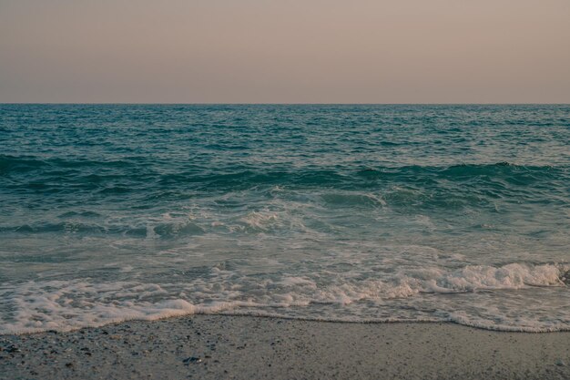 Wellen des Mittelmeers rollen zum türkischen Sandstrand, wunderschöner türkischer Abend