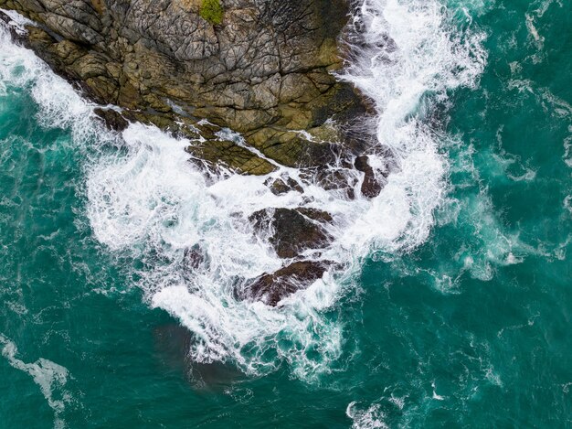 Wellen krachen auf Felsen am Meeresufer. Draufsicht auf Meeresoberflächenwellen im Hintergrund