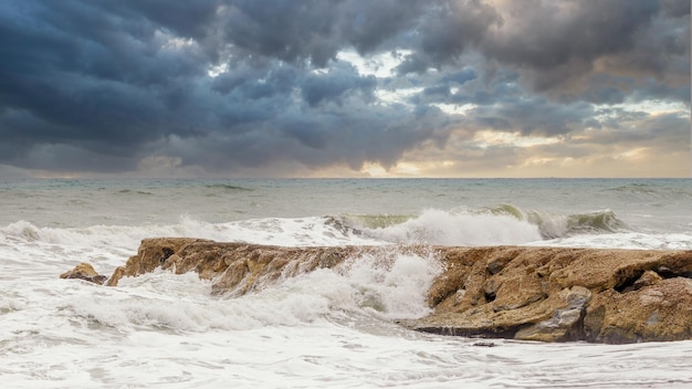 Foto wellen krachen gegen die felsen mit gewitterwolken bei sonnenuntergang an den stränden der costa del sol