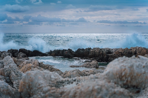 Wellen plätschern gegen die felsige Küste und bilden natürliche Pools. Dramatische Wolkenlandschaft