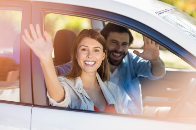 Wellenartig bewegende Hände des glücklichen Paars während im Auto